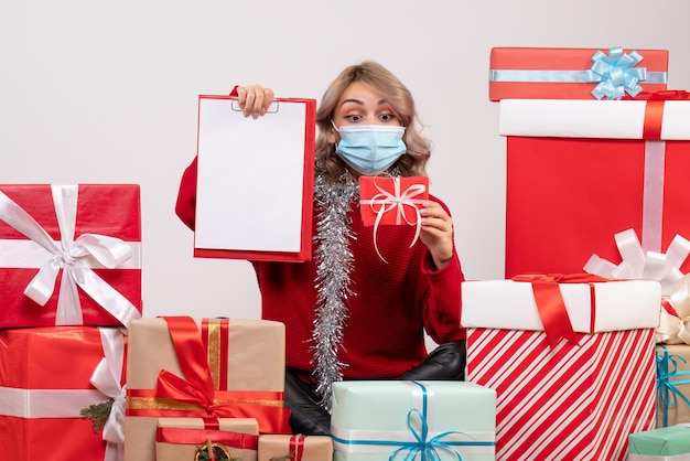 Vista frontal de las mujeres jóvenes sentados alrededor de regalos con nota