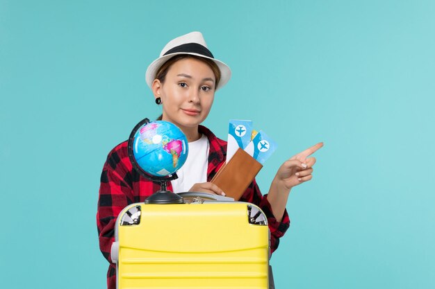 Vista frontal de las mujeres jóvenes sosteniendo boletos en el piso azul viaje de vacaciones viaje femenino viaje