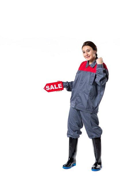 Vista frontal de las mujeres jóvenes en uniforme sosteniendo la placa de venta y sonriendo sobre fondo blanco.