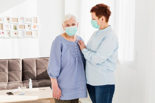 Vista frontal de las mujeres mayores con máscaras médicas en casa