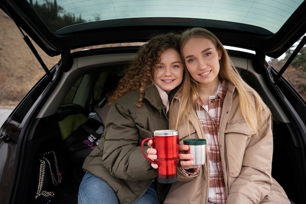 Vista frontal de las mujeres sonrientes en el baúl del auto