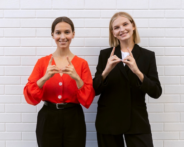 Foto gratuita vista frontal de mujeres sonrientes con lenguaje de señas