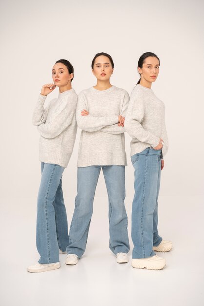 Vista frontal de mujeres en suéteres y jeans posando para retratos minimalistas.