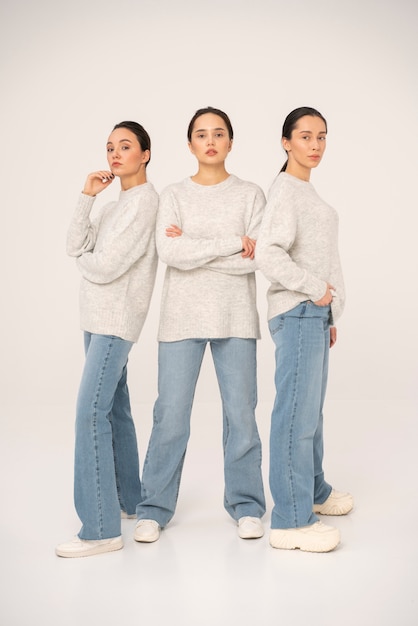 Vista frontal de mujeres en suéteres y jeans posando para retratos minimalistas.