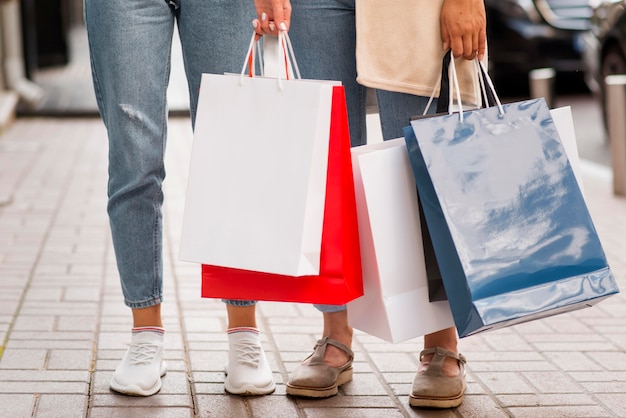 Vista frontal, de, mujeres, tenencia, bolsas de compras, en la calle