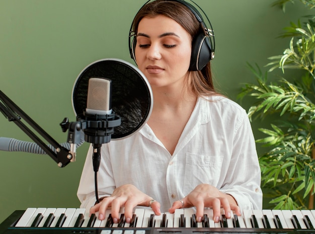 Vista frontal del músico femenino cantando y tocando el teclado del piano