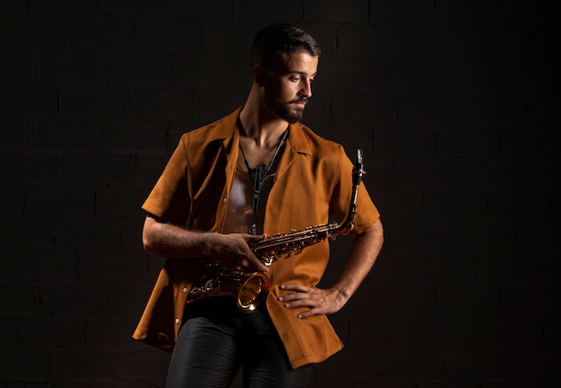 Foto gratuita vista frontal del músico masculino posando con saxofón