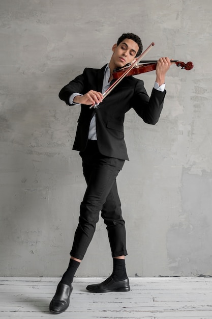 Vista frontal del músico masculino tocando el violín