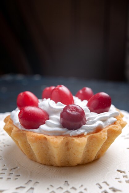 Vista frontal muy cercana delicioso pastel con crema y frutos rojos en la superficie oscura pastel galleta de frutas