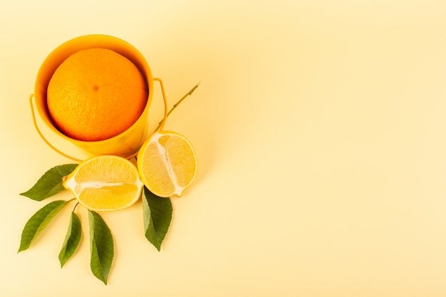 Una vista frontal de naranja entera dentro de la canasta de naranja junto con rodajas de limón maduro, dulce y jugoso meloso aislado en el fondo crema de cítricos de naranja