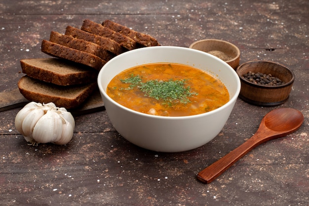 Vista frontal naranja sopa de verduras con panes y ajo en marrón, sopa de comida