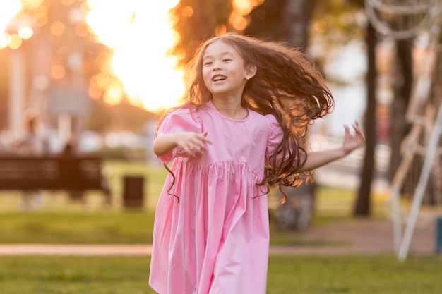 Vista frontal niña asiática con pelo largo corriendo en el parque