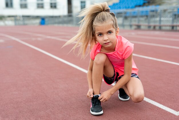 Vista frontal de la niña atando sus cordones