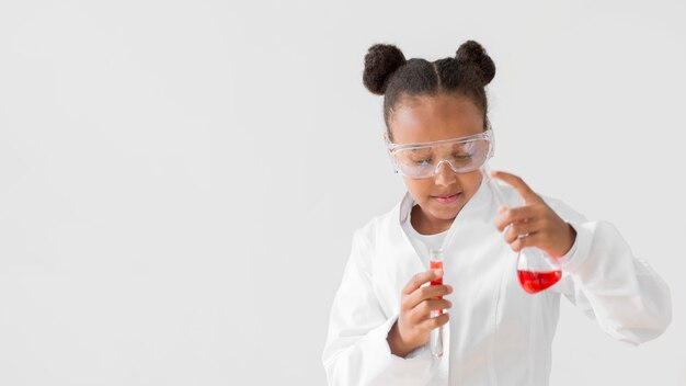 Vista frontal de la niña científico con bata de laboratorio y gafas de seguridad