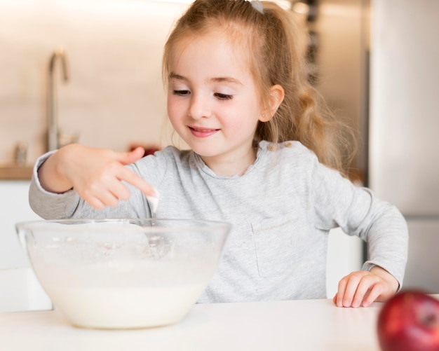 Vista frontal de niña cocinando en casa