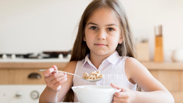 Vista frontal de la niña comiendo cereales para el desayuno