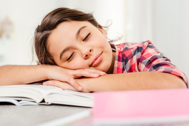 Vista frontal niña durmiendo en el libro