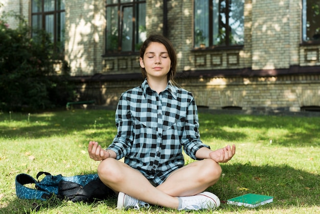 Vista frontal de la niña de la escuela secundaria meditando