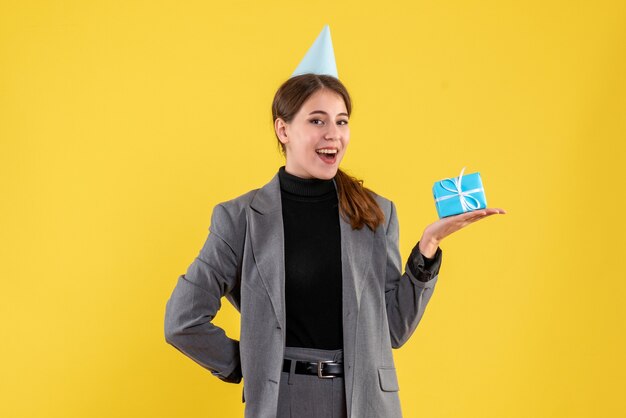 Vista frontal niña feliz con gorro de fiesta sosteniendo su regalo