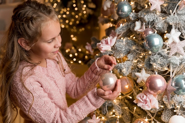 Vista frontal de la niña feliz con regalos y árbol de Navidad