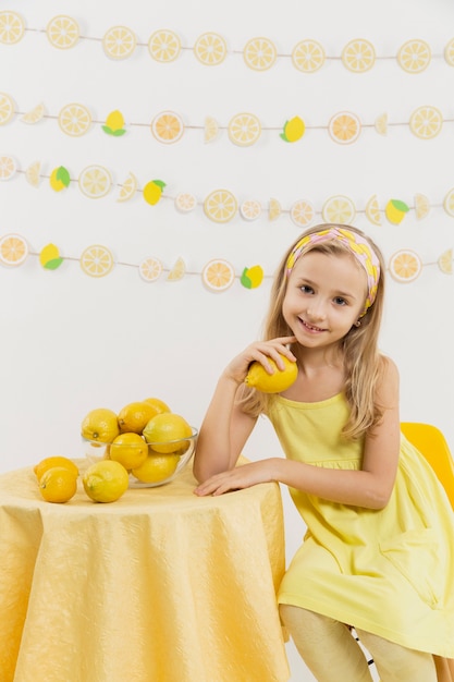 Vista frontal de la niña feliz sosteniendo un limón y sonriendo