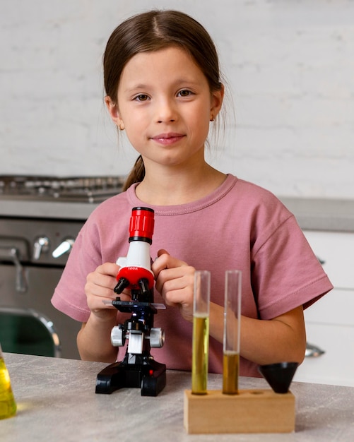 Vista frontal de la niña haciendo experimentos con microscopio