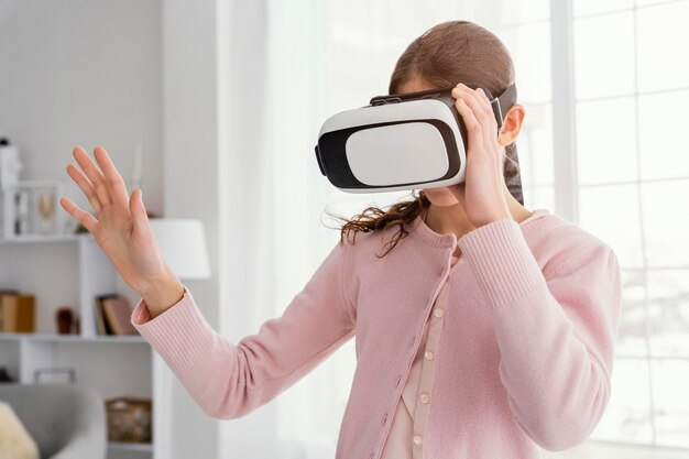 Vista frontal de la niña jugando con casco de realidad virtual