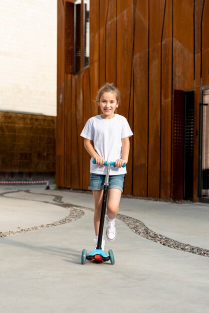 Vista frontal de la niña montando scooter azul