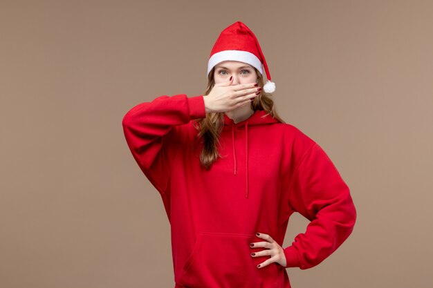 Vista frontal de la niña de Navidad con capa roja en el modelo de escritorio marrón Navidad de vacaciones