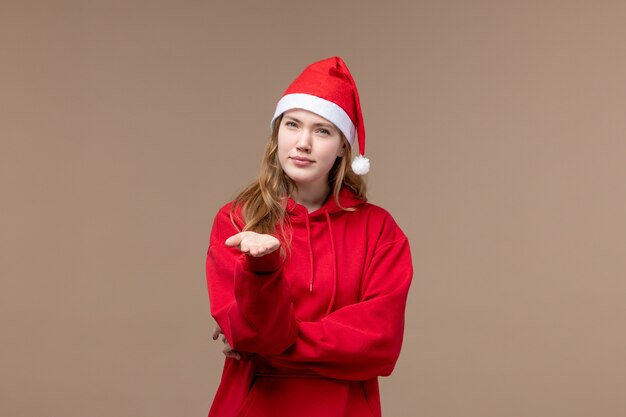 Vista frontal de la niña de Navidad con cara confundida sobre fondo marrón mujer vacaciones Navidad