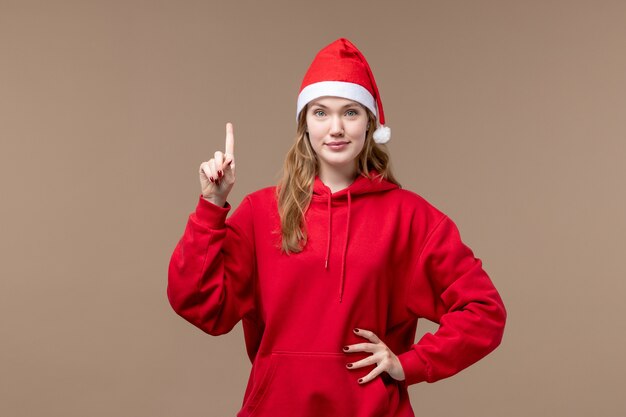 Vista frontal niña de navidad con cara sonriente sobre fondo marrón vacaciones año nuevo navidad