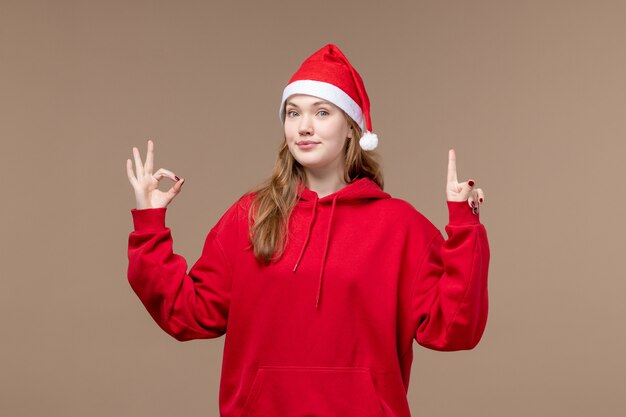 Vista frontal de la niña de Navidad con expresión encantada en el escritorio marrón mujer vacaciones Navidad