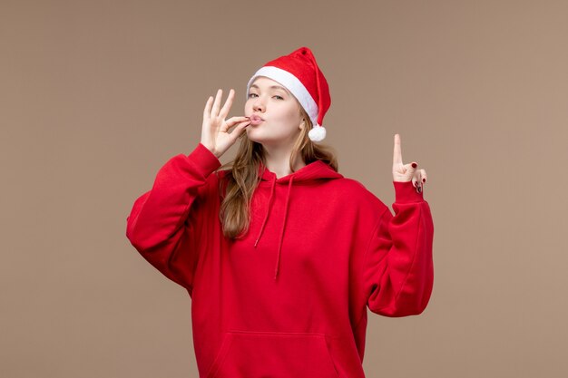 Vista frontal de la niña de Navidad con expresión encantada sobre fondo marrón mujer vacaciones Navidad