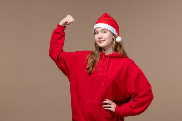 Vista frontal de la niña de Navidad sonriendo y flexionando sobre fondo marrón vacaciones Navidad emoción