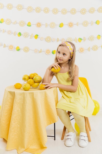 Foto gratuita vista frontal de la niña pensando posando mientras sostiene un limón