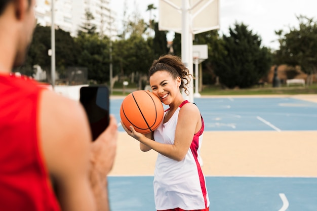 Foto gratuita vista frontal de la niña posando con pelota de baskeball