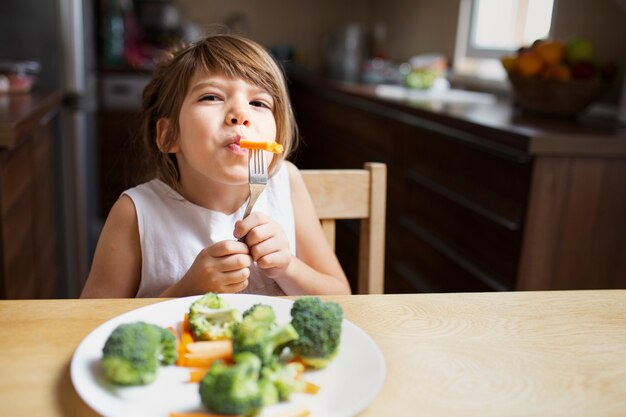 Vista frontal de la niña que tiene verduras