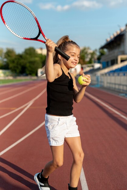 Vista frontal de niña con raqueta de tenis