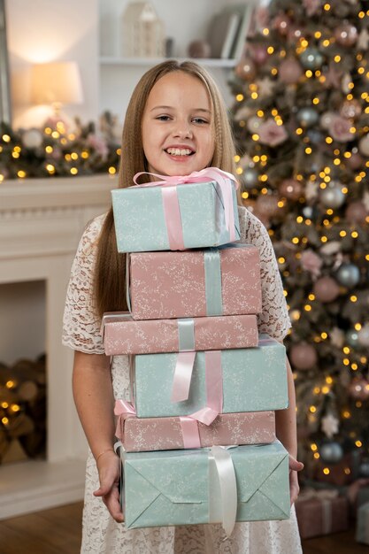 Foto gratuita vista frontal de la niña con regalos de navidad