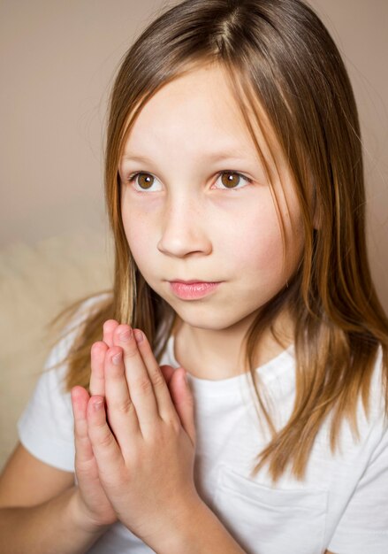 Vista frontal de la niña rezando