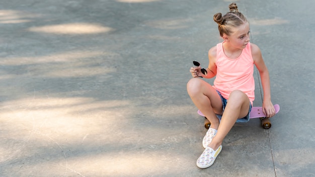 Vista frontal de la niña sentada en patineta