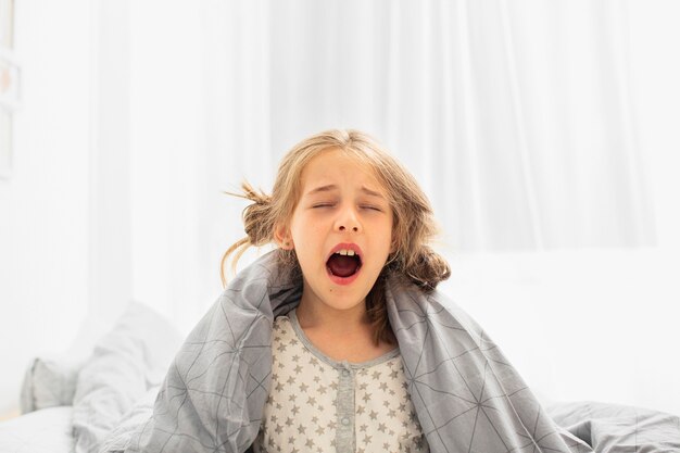 Vista frontal de la niña sonriente en la cama