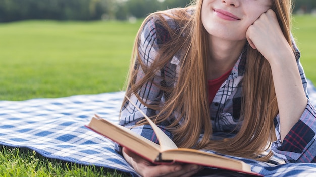 Vista frontal niña sonriente leyendo un libro