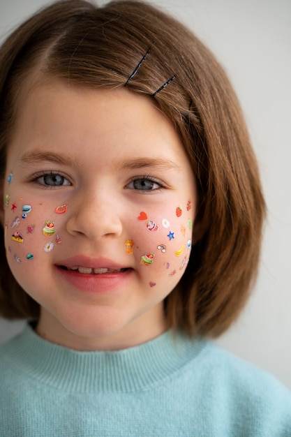 Foto gratuita vista frontal niña sonriente con pegatinas en la cara