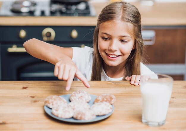 Vista frontal niña sonriente tomando una deliciosa galleta