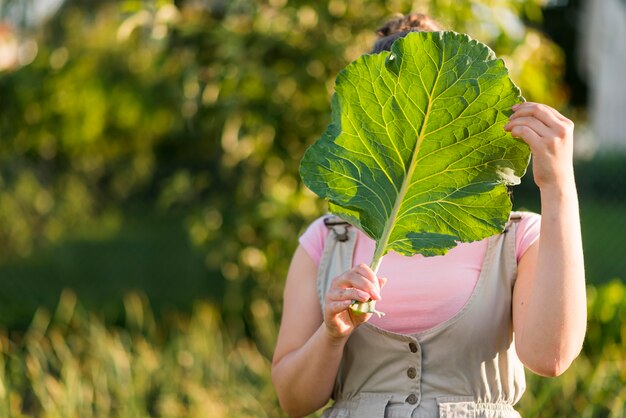 Vista frontal niña sosteniendo hojas de lechuga