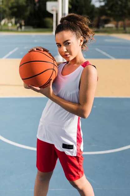 Vista frontal de la niña sosteniendo la pelota de baloncesto