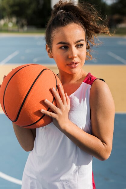 Vista frontal de la niña sosteniendo la pelota de baloncesto