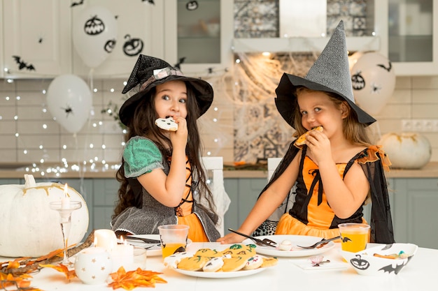 Foto gratuita vista frontal de las niñas comiendo galletas de halloween