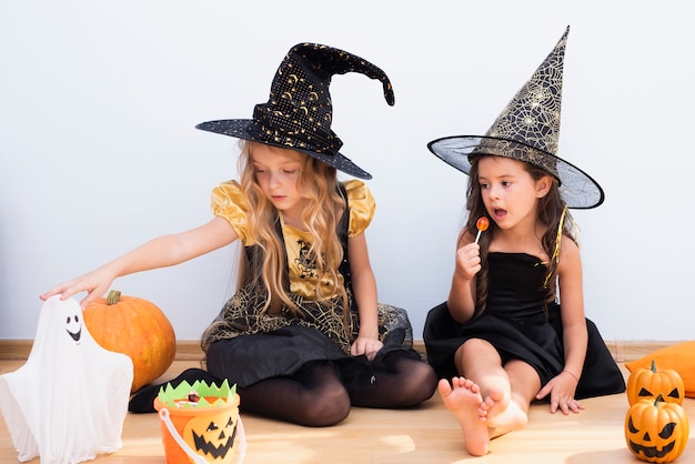 Vista frontal niñas sentadas en el piso en halloween